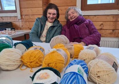 Two ladies smiling with balls of wool in the foreground at Knitting Group